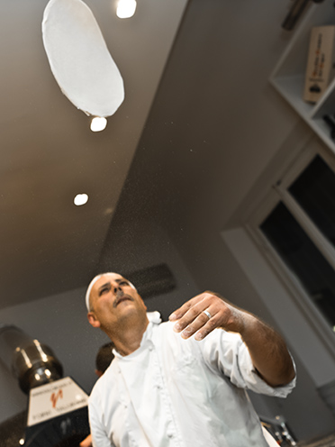 # ulisse albiati food photographer: a genuine pizza maker with his flying pizza. Da Michele restaurant in Lastra a Signa, Tuscany.