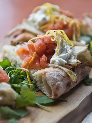 # ulisse albiati food photographer: a slice of special pizza with salmon, lemon zest, stracciatella Italian cheese and endive as main course. Le Pavoniere restaurant in Florence, Tuscany.