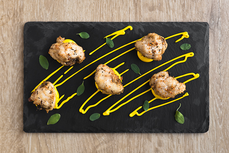 # ulisse albiati food photographer: bites of angler fish with almond breading and saffron mayonnaise, served on a foil of slate, as second course. Le Pavoniere restaurant in Florence, Tuscany.