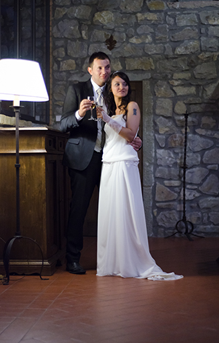 # The newly-married couple drinks a toast in an elegant and antique tuscan hall.